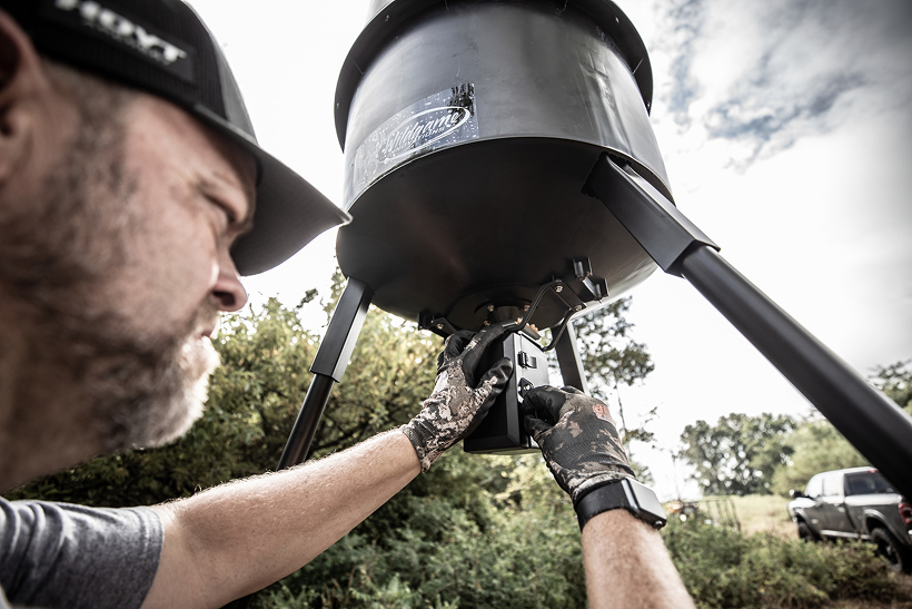 Hunter servicing a deer feeder spinner plate to keep raccoons out