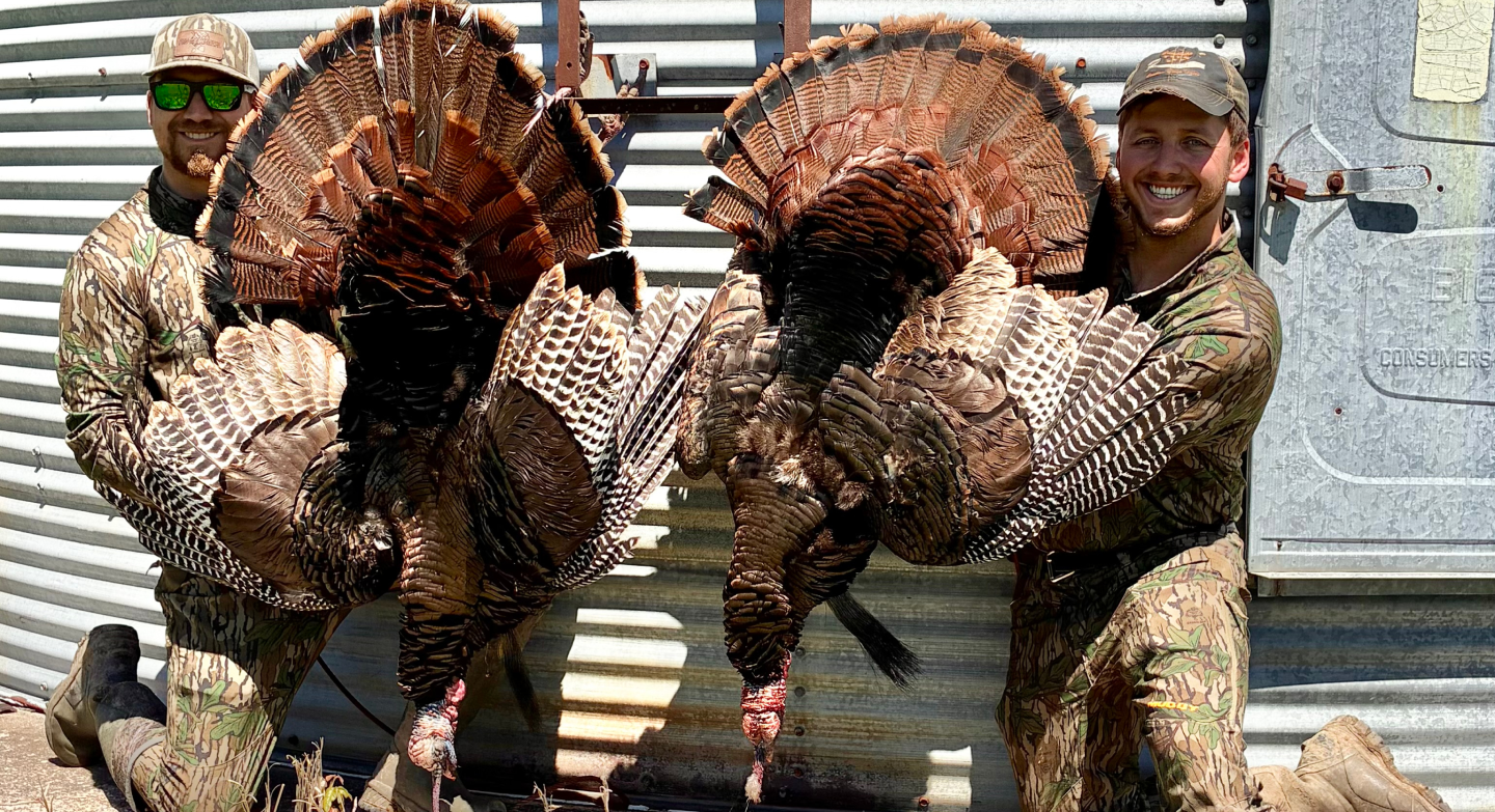The two Double D Hunting founders in camouflage holding a pair of harvested Missouri wild turkeys