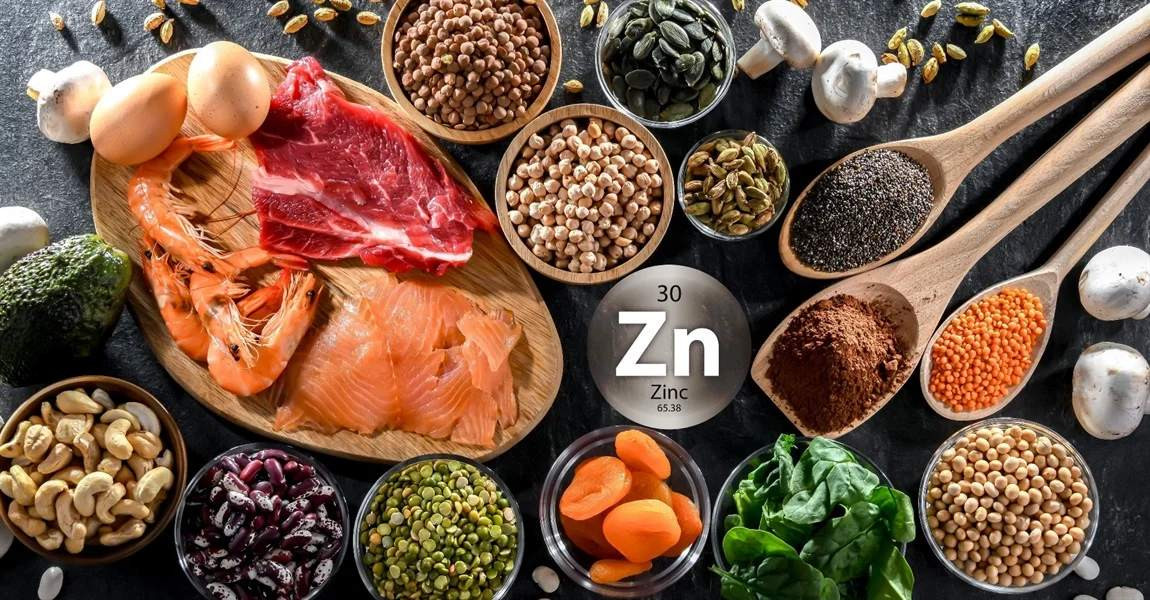 Zinc-rich foods including oysters, pumpkin seeds, nuts and lean meat on a wooden board, for male fertility support.