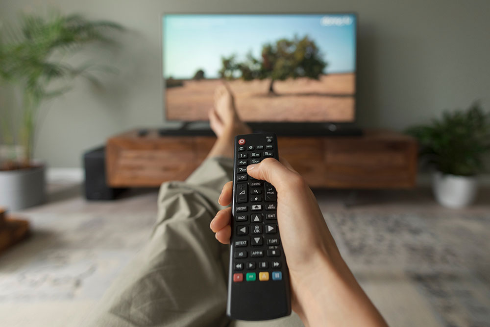 Person pointing a remote control at a television