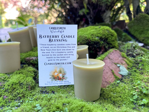 Real bayberry votive candle and a card printed with the traditional bayberry candle blessing sitting on a bed of green moss surrounded by more bayberry votives in a nature setting.