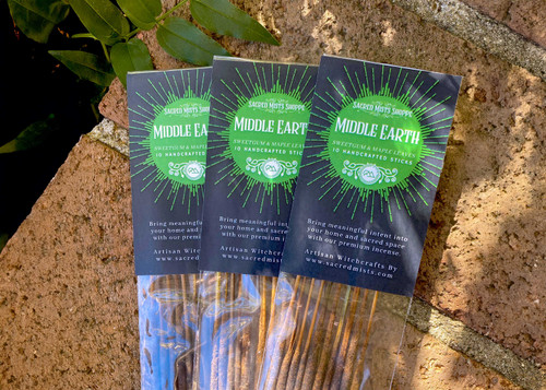 Three packs of middle earth handmade incense lie on brickwork in filtered sunlight