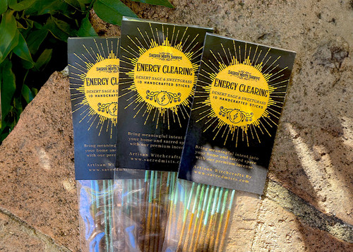 Three packs of energy clearing handmade incense lie on brickwork in filtered sunlight