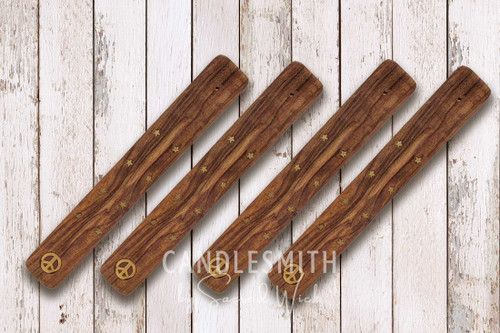 Four wood stick incense holders lie on a light-colored, distressed wood table, shown from above to display the design.