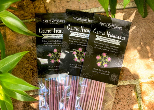 Three packs of celtic highlands handmade incense lie on brickwork in filtered sunlight