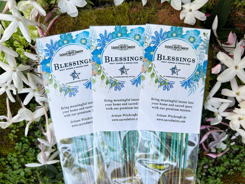 Three packs of Blessings Handmade Incense lying on a bed of flowers and brick. Fragrance notes for this incense are night-blooming jasmin, damask rose, and creamy musk.