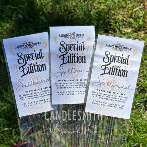 Three packages of Spellbound handcrafted incense sticks arranged on sunlit grass, showing the Sacred Mists Shoppe packaging and dark incense sticks inside.