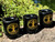 Three black ceramic chime and mini taper candle holders with gold tree of life printed, resting on a rock with greenery in the background.