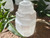 Macro close-up of a selenite crystal candle holder with its natural shimmer, set on brickwork with greenery