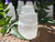 Close-up of a selenite crystal candle holder on brickwork with greenery and additional holders in the background
