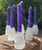Group of selenite crystal candle holders with purple mini chime candles arranged on brickwork, candles not included
