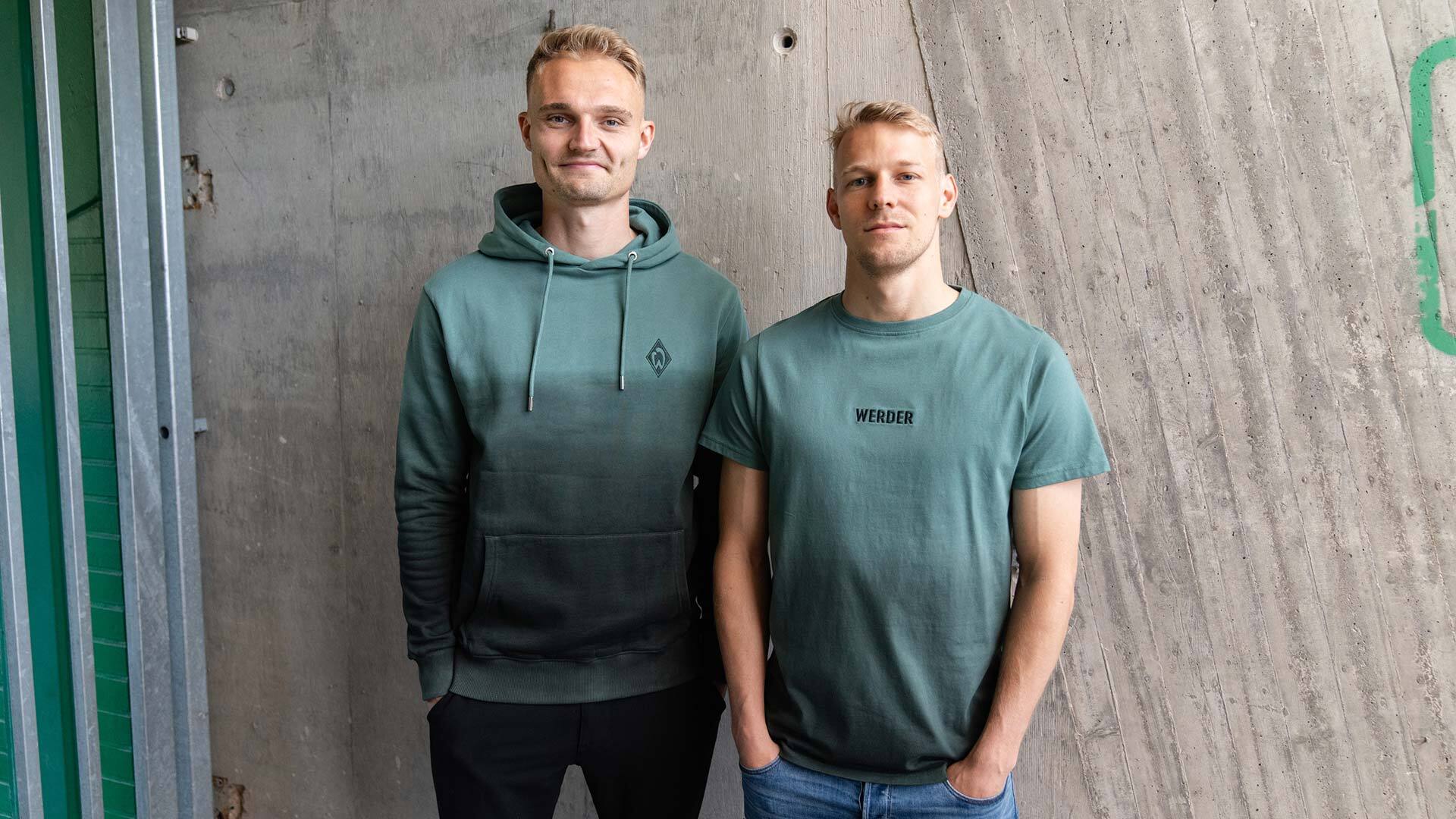 Zwei Spieler tragen ein T-Shirt und einen Hoodie in Grün aus der Kollektion Farbverlauf.