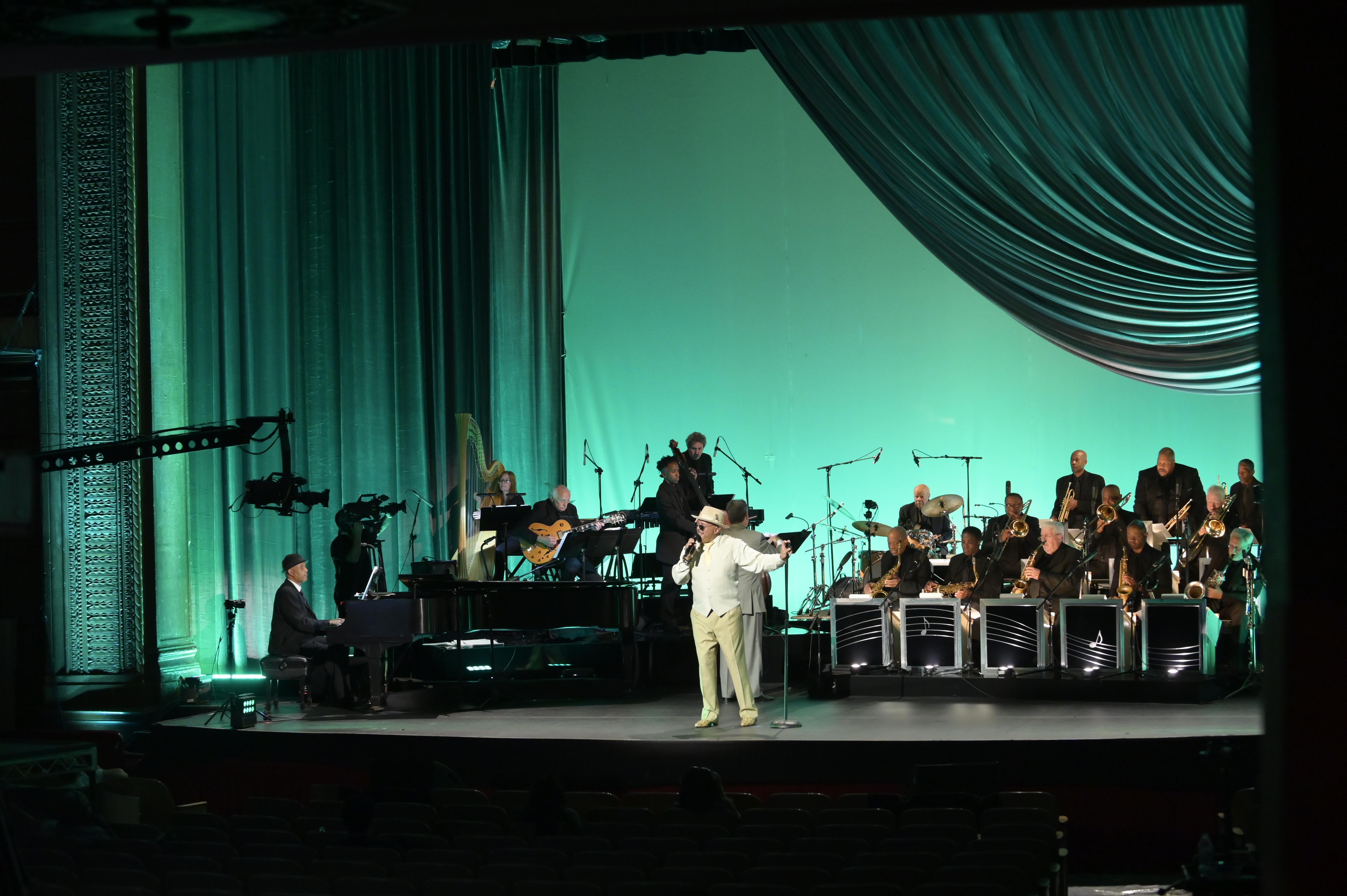 man in white singing onstage