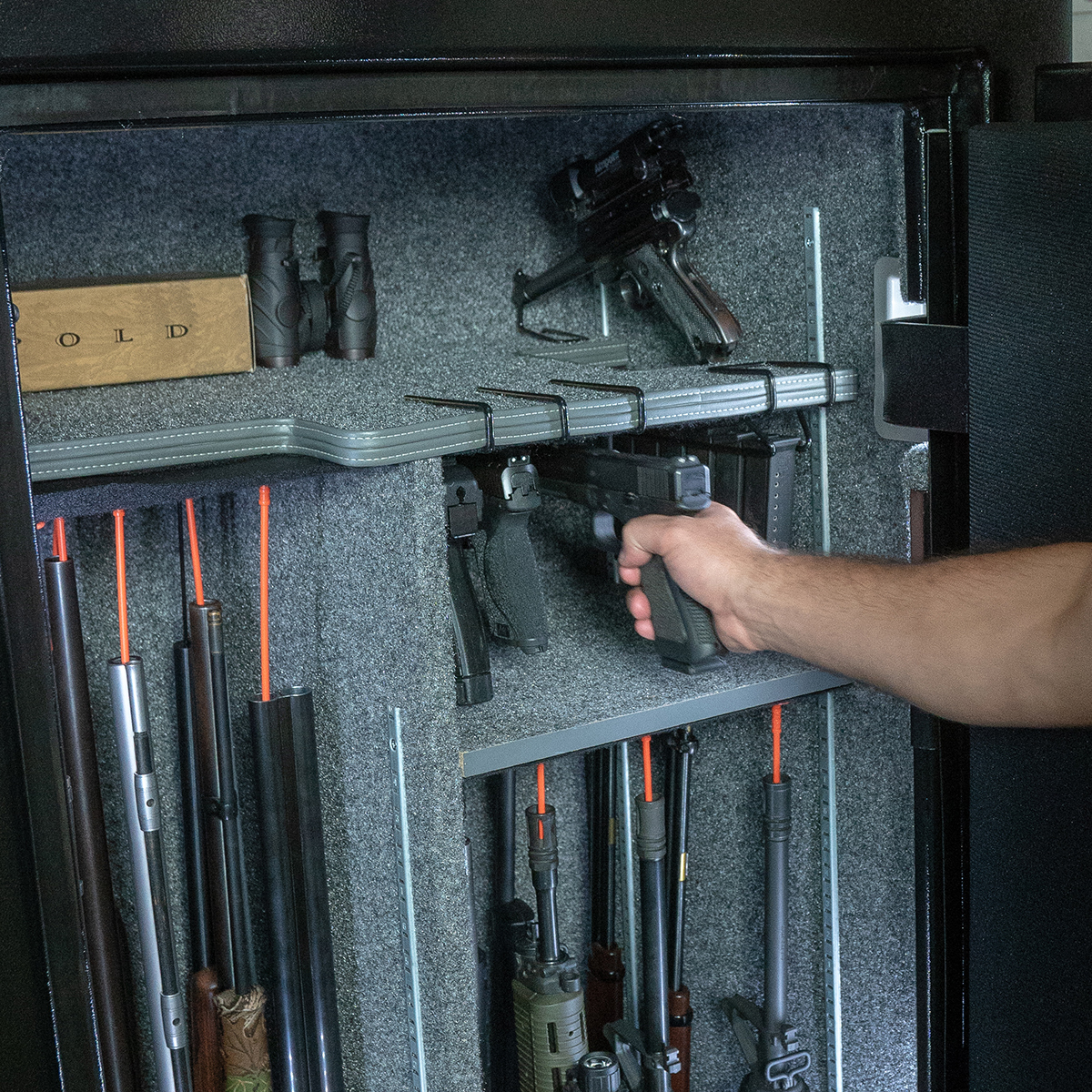 Pistol being pulled from handgun hanger inside a gun safe