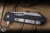 Heretic Knives Jinn Button Lock Flipper Knife Black Aluminum 3" MagnaCut Wharncliffe Battleworn H213-5A