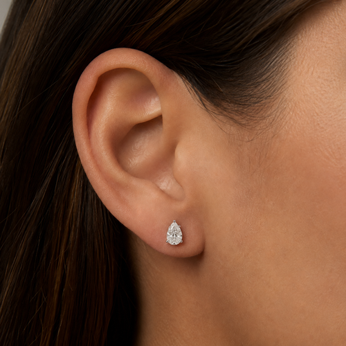Woman wearing 2 carat pear lab grown diamond stud earring, shown on ear for scale, white gold