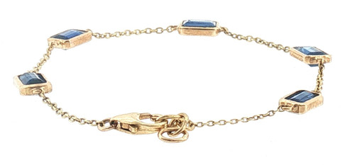 Angled full view of a 14K yellow gold station chain bracelet featuring five rectangular deep blue sapphires spaced evenly along a delicate gold chain.