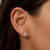 Woman wearing 2 carat pear lab grown diamond stud earring, shown on ear for scale, white gold