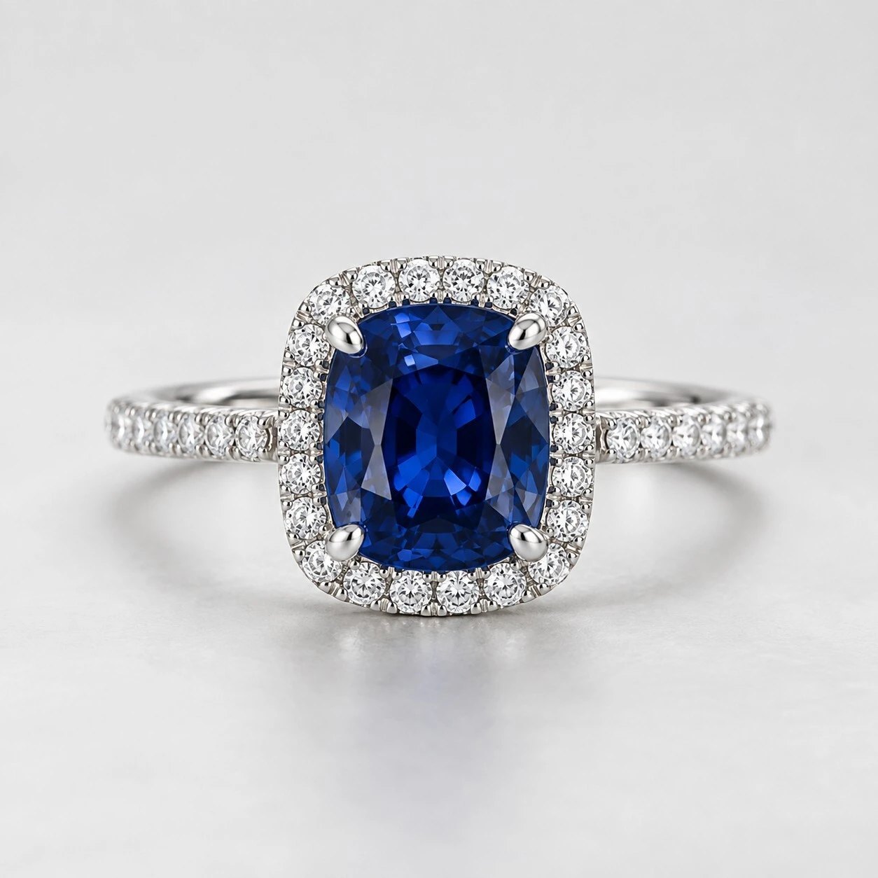 Cushion-cut blue sapphire engagement ring with diamond halo and pave set band