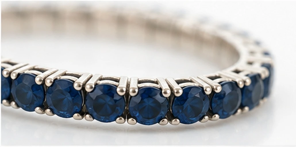 Macro detail of round blue sapphires held in four-prong settings along a 14K white gold line bracelet