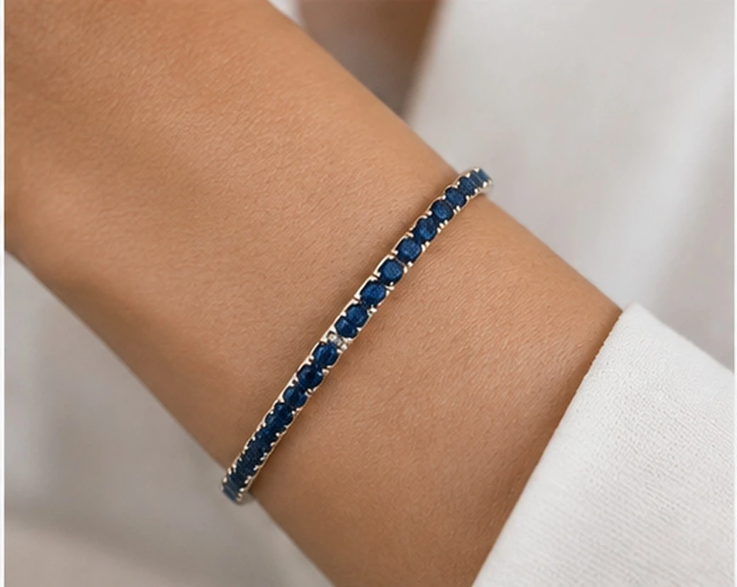 Woman wearing a deep blue sapphire line bracelet in 14K white gold with a white silk cuff