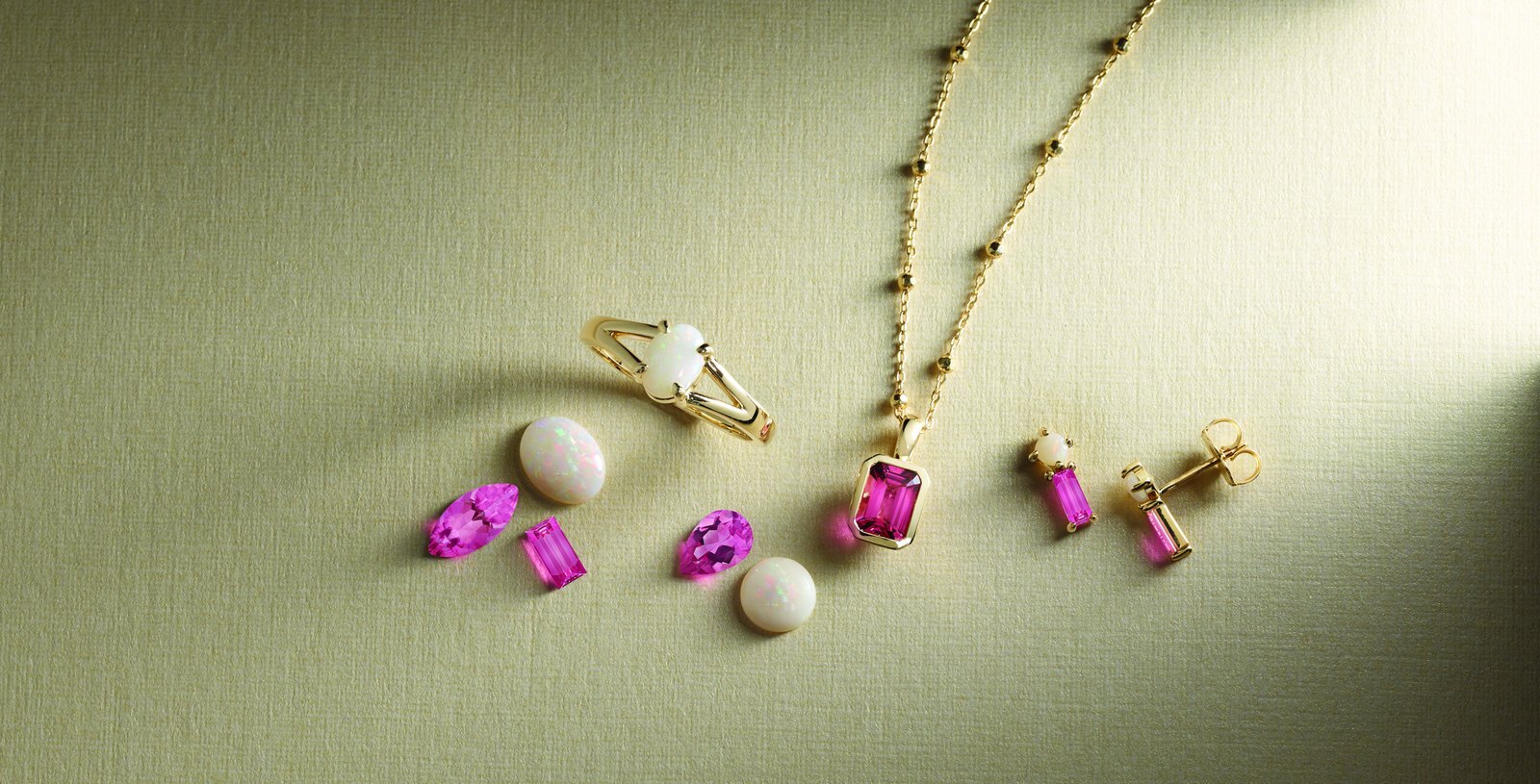 White opal ring, loose opal cabochons, pink tourmaline gems, a bezel-set pink tourmaline pendant and opal and pink tourmaline drop earrings in yellow gold
