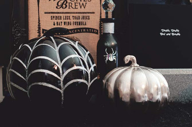 A Halloween Party Table with black and silver pumpkins and witches brew