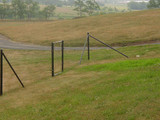 A far away shot of components of a fence in a field.