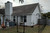 The back of a house with a fence keeping a cat safe.