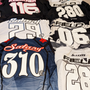 Six jerseys laid out. They are a variety of colours, and all have different names across the backs of the shoulders. There are large numbers under each name.