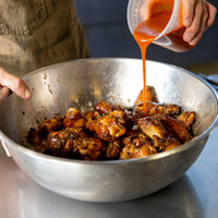 Prepping the smoked chicken wings in sauce.