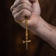 Shields of Strength Stainless Steel Gold Plated Nail Cross Necklace-John 19:30  Man's hand holding the necklace