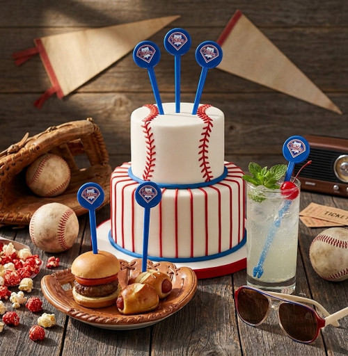 Philadelphia Phillies MLB swizzle sticks used as baseball-themed cake toppers, drink stirrers in a refreshing soda, and food picks in sliders and pretzel dogs on a rustic wooden table with vintage baseball gear