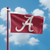 Alabama Crimson Tide NCAA 3' x 5' Logo Flag - Outdoors flying on a crimson flag pole showing the blue sky