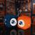 Denver Broncos NFL Orange & Blue Plush Fuzzy Logo Dice – 3" Hanging Fan Décor with Team Logo and Colors - Displayed on a black table in a football fan room