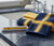 WVU - West Virginia University Collegiate Snap Together Travel Toothbrush Cover - Displayed on a bathroom countertop next to blue and gold color towels.