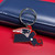 New England Patriots NFL Home State Rubber Logo Keychain - On a red table next to a Patriots Blue color wallet