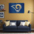 LA Rams Football Wall Flag - Indoors - Hanging on a Gold Color wall above a Rams Blue Color Couch in a Football Fan Cave Room