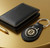 Boston Bruins NHL Black Leather Key Fob Keychain - Displayed on a yellow gold color table, next to a black wallet