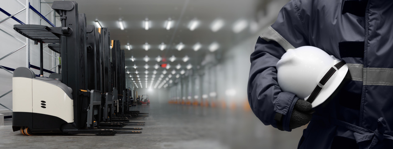Electric reach trucks lined up in a cold storage warehouse with an operator in insulated cold-weather gear