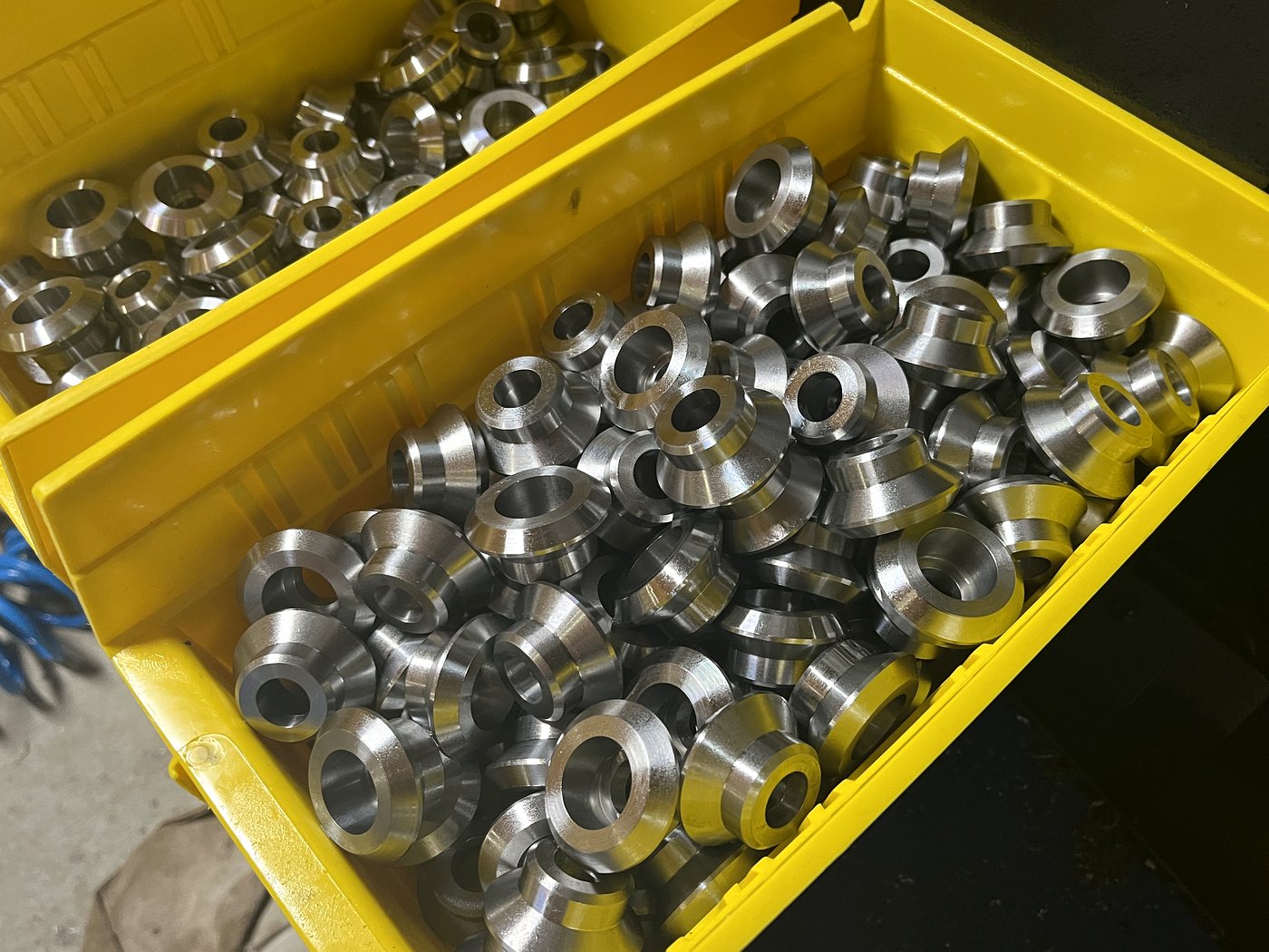 Two bins of turned flanged bushings