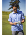 Man standing on a golf course while wearing a Chelan Cutter & Buck Pike Eco Flora Print Recycled Mens Big & Tall Polo Thumbnail Image