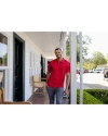 A man standing on a porch while wearing a Red Cutter & Buck Prospect Eco Textured Stretch Recycled Mens Short Sleeve Polo Thumbnail Image
