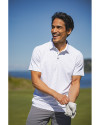 A man playing on a golf course while wearing a White Cutter & Buck Virtue Eco Pique Tile Print Recycled Mens Polo Thumbnail Image
