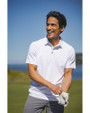 A man playing on a golf course while wearing a White Cutter & Buck Virtue Eco Pique Tile Print Recycled Mens Polo