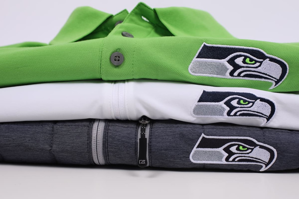 A Seattle Seahawks polo, jacket, and pullover neatly stacked together