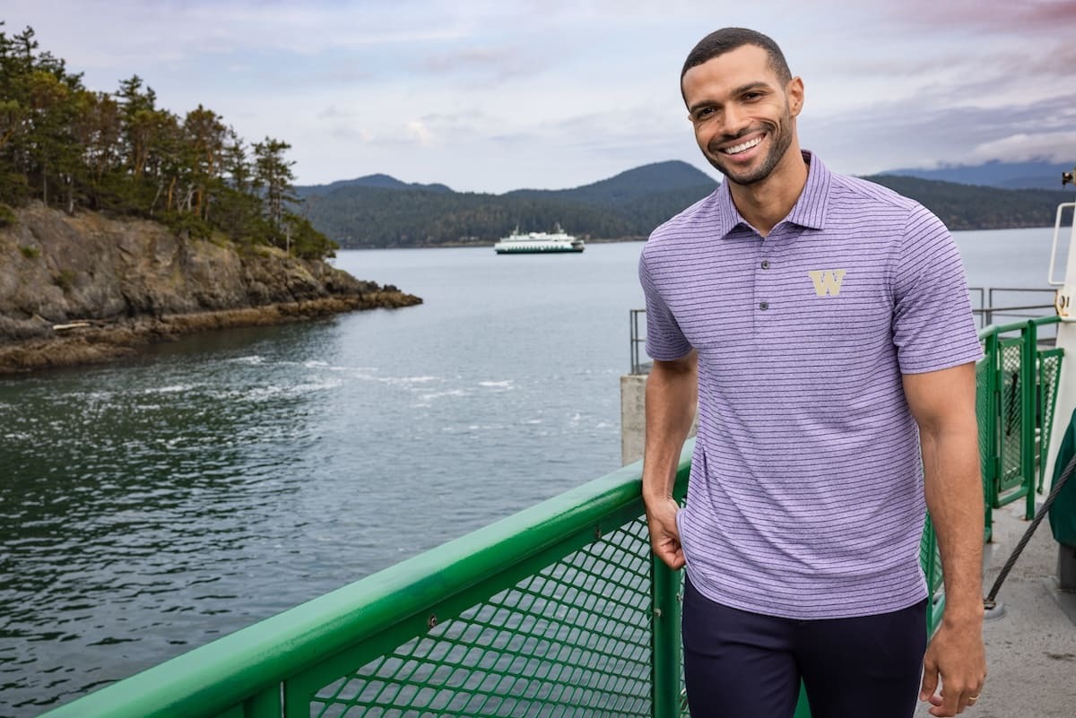 A suave man wearing a purple Washington Huskies polo on a dock 