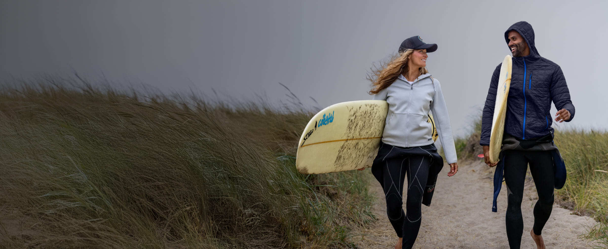 Man and woman walking on beach wearing Cutter & Buck jackets and layers.