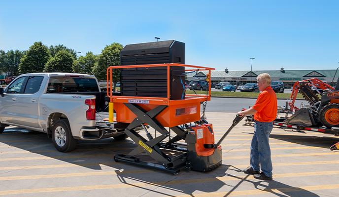 Man using pallet jack to move a loading dock near a pickup truck