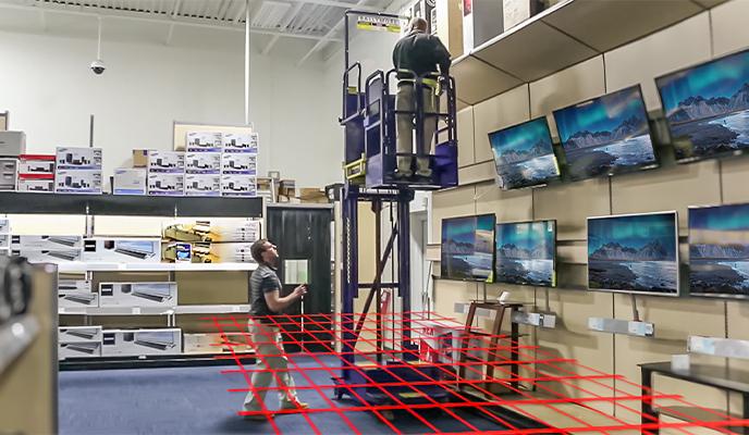 An elevated lift in an electronics store casting an animated laser grid detecting a nearby shopper
